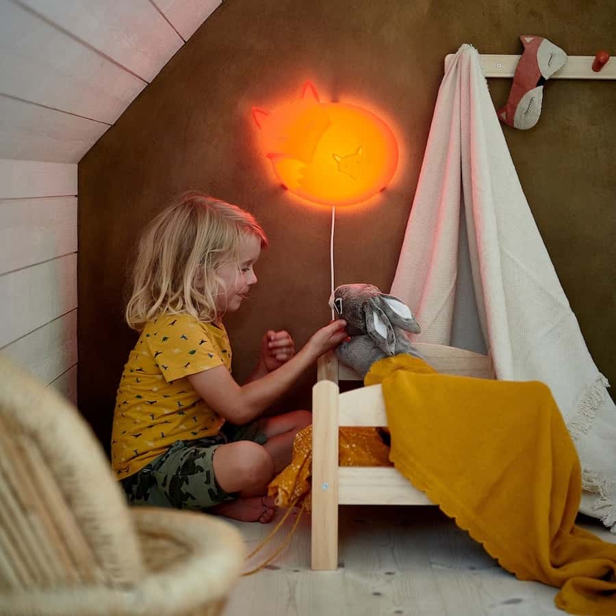 girl playing with rabbit and wooden doll bed