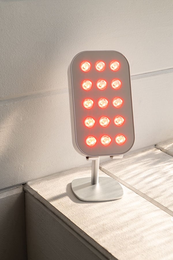 image of red light therapy device on and on a small metal stand on top of a furniture edge