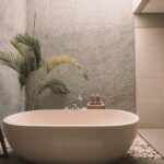 luxury bath rug featured image of high-end stand along bathtub with cement walls and tropical plant on left corner