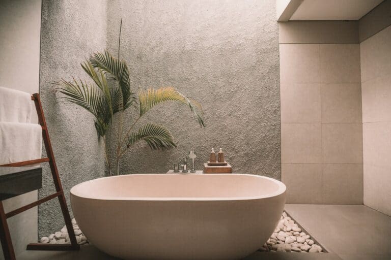 luxury bath rug featured image of high-end stand along bathtub with cement walls and tropical plant on left corner