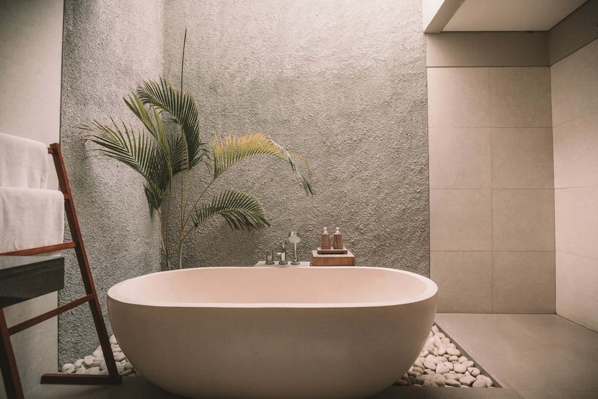 luxury bath rug featured image of high-end stand along bathtub with cement walls and tropical plant on left corner